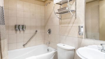 Een badkamer met een bad, toilet en wastafel, met een handdoekhouder en planken boven de wastafel.