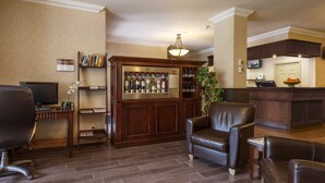 A living room with a TV, a bar area with a refrigerator, and leather seating.