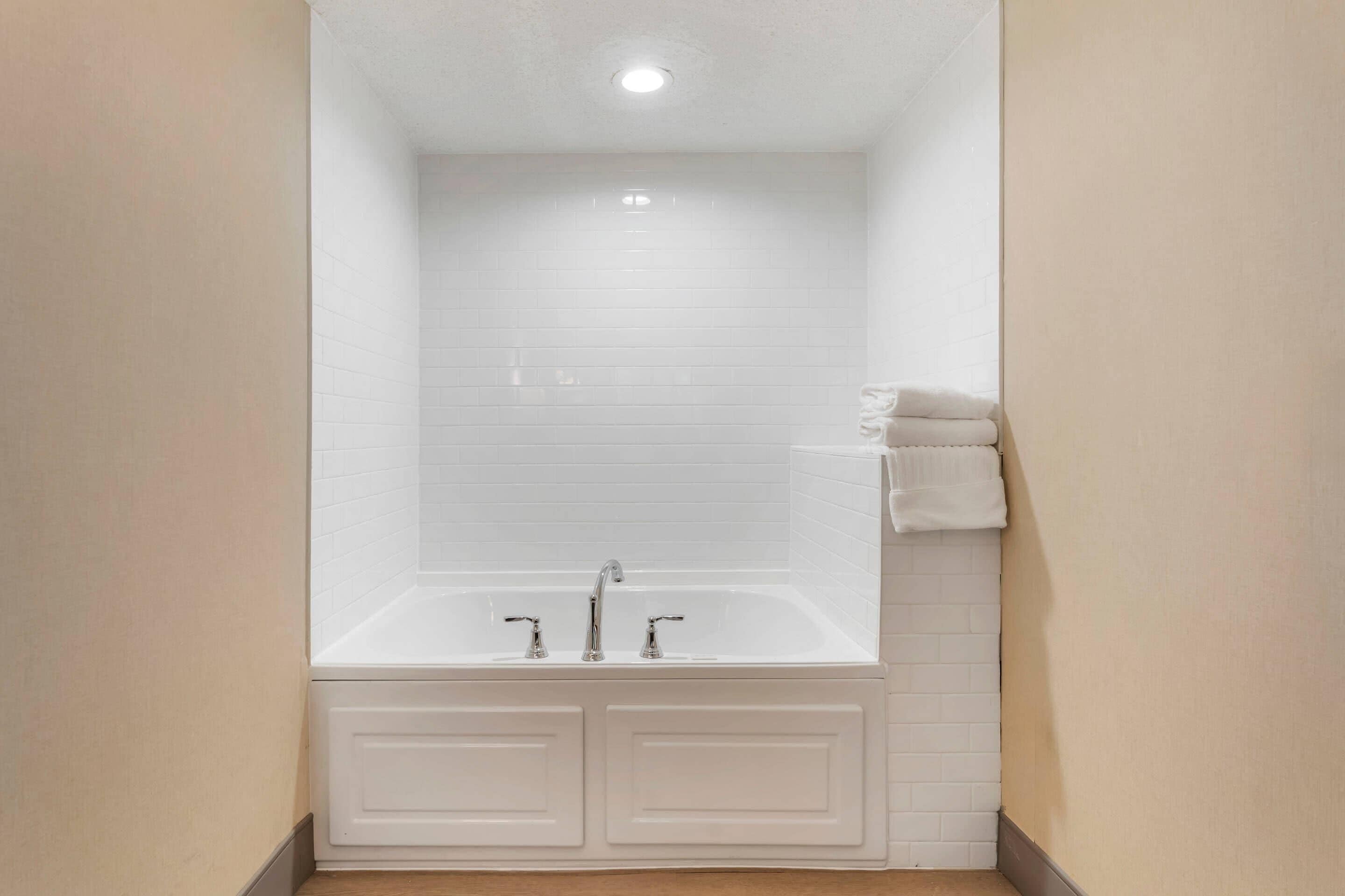 A bathroom with a white bathtub, a white sink, and a towel rack.