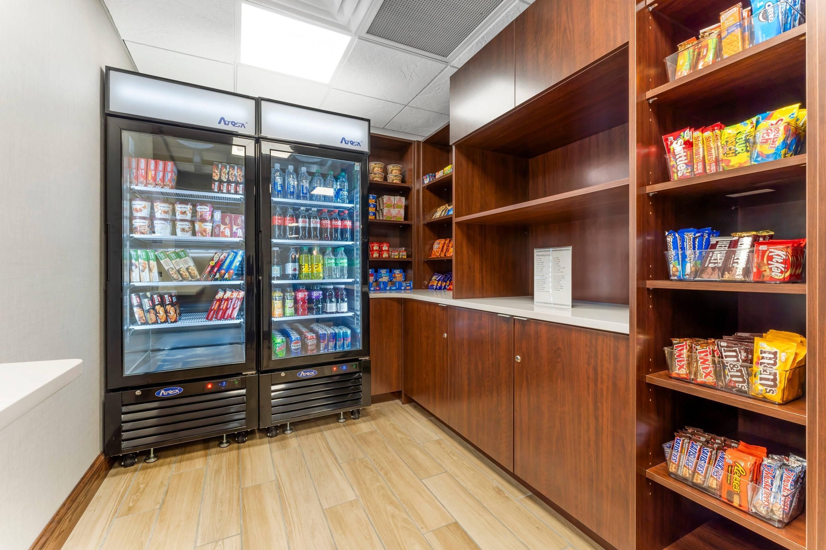 A vending area with two refrigerated beverage dispensers and shelves stocked with snacks.