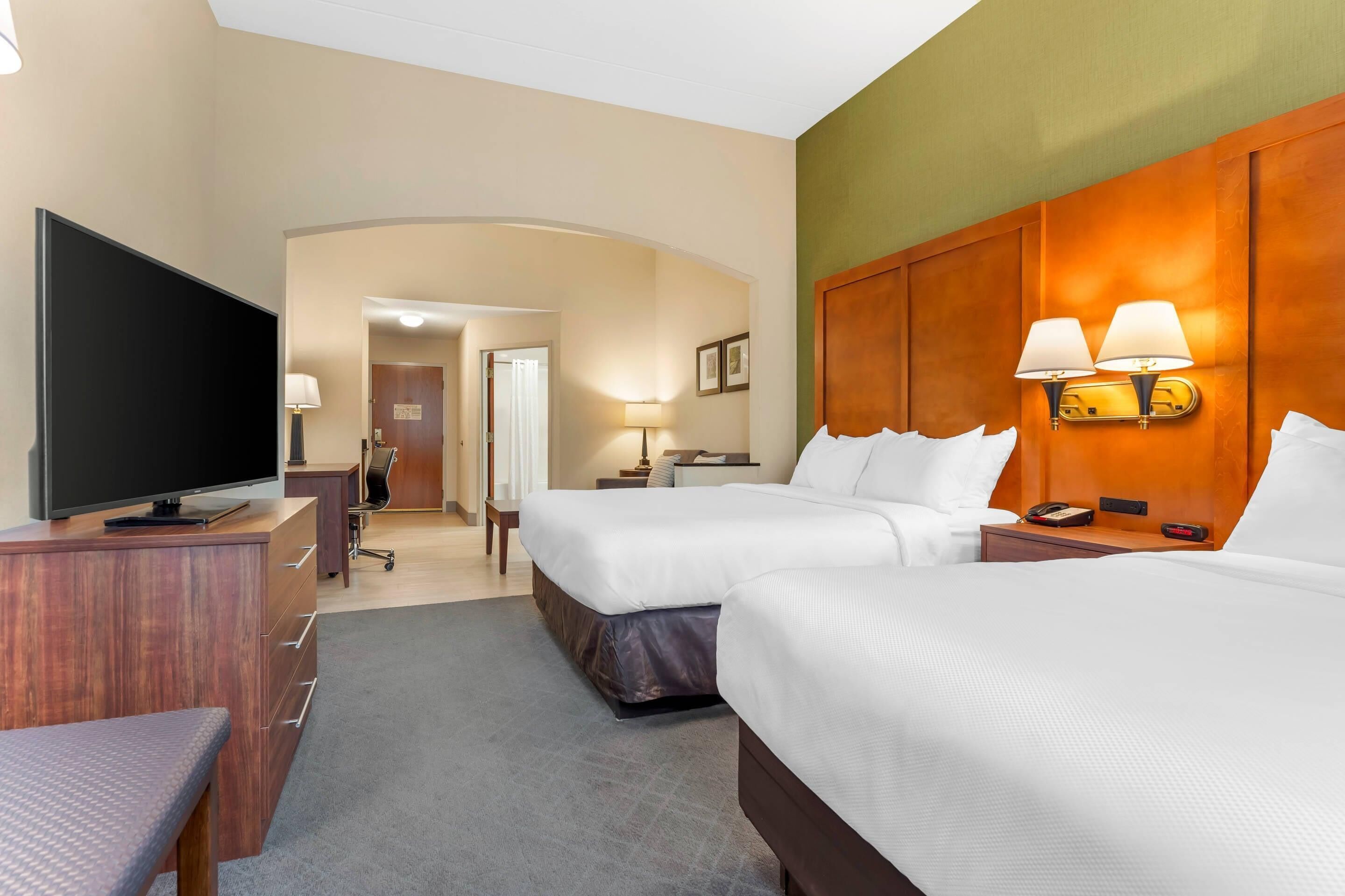 A hotel room with two beds, a TV, a desk, and a chair.