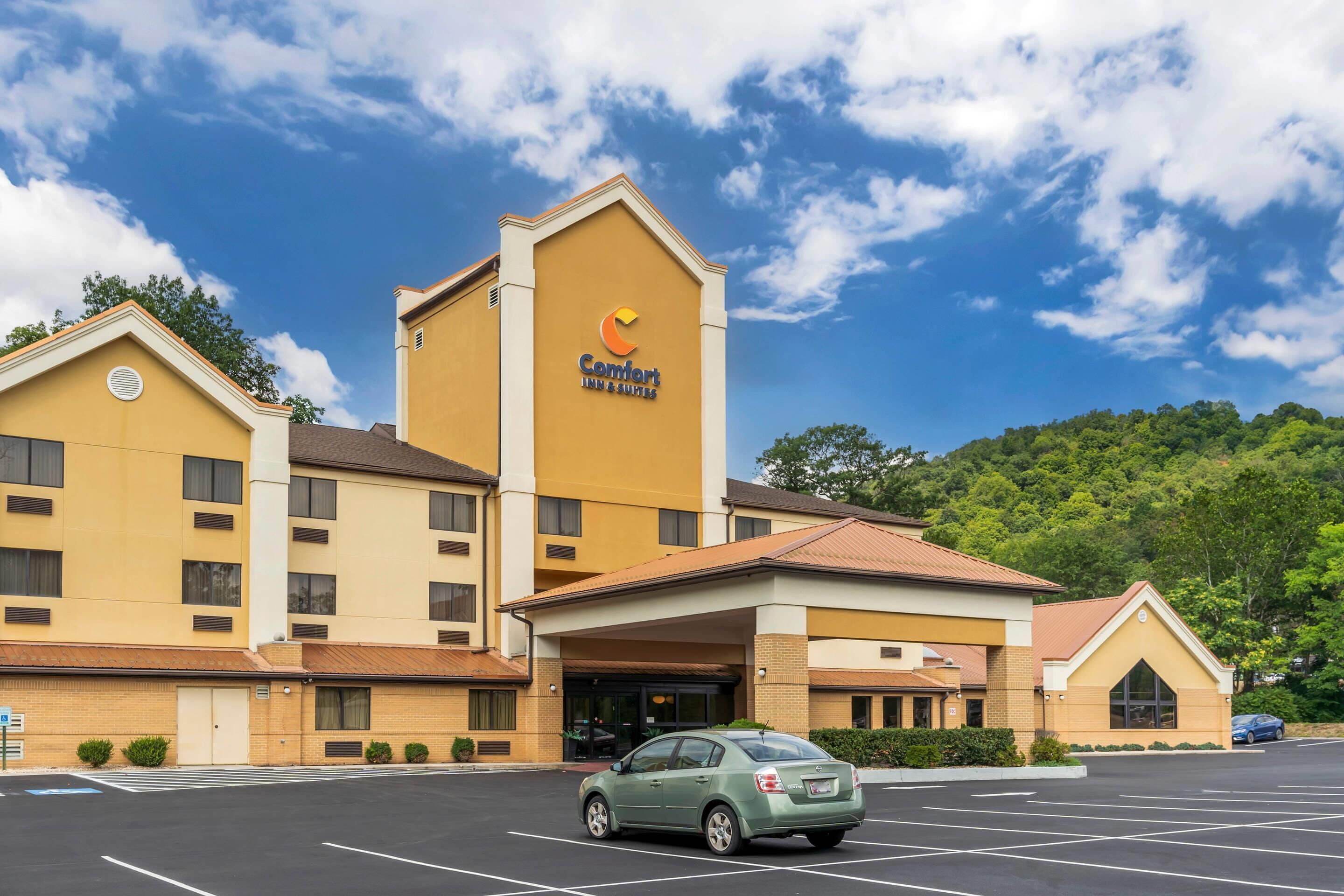 A Comfort Inn & Suites hotel with a parking lot and a green car parked in front.