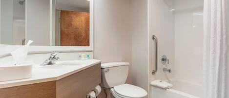 Un baño moderno con lavabo, espejo, inodoro y ducha.