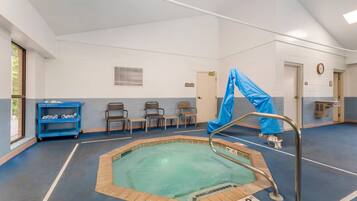 A swimming pool area with a blue tarp, a metal pool ladder, and a blue cart with towels.