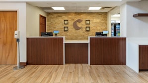 A reception area with a wooden reception desk, a stone wall with a crescent moon design, and a floor with wooden planks. - Comfort Inn & Suites LaVale - Cumberland (Cumberland)