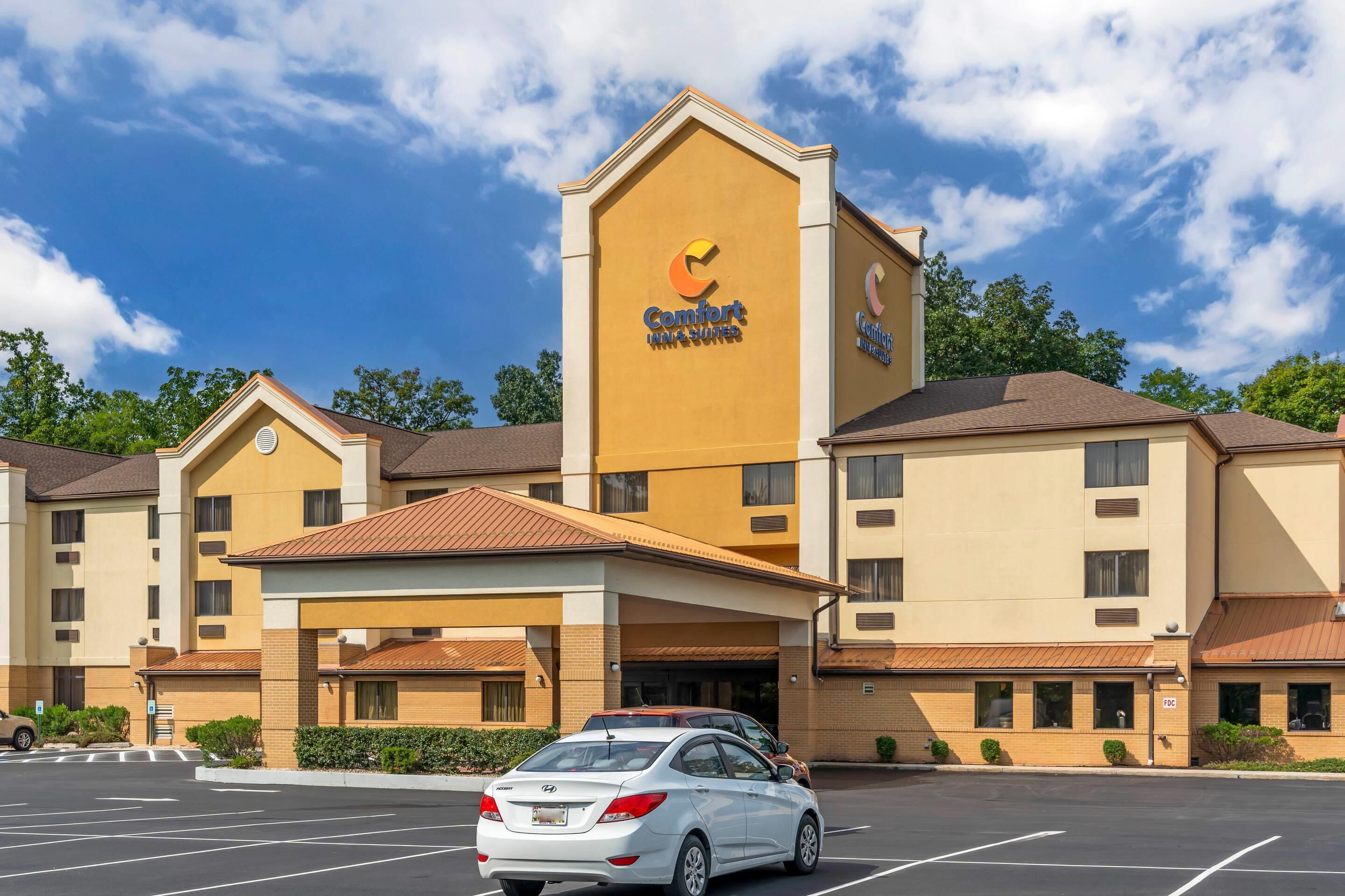 Ein Comfort Inn Hotel mit einem gut sichtbaren 'Comfort Inn' Schild, einem Parkplatz und einem Gebäude mit vielen Fenstern und einem braunen Dach.