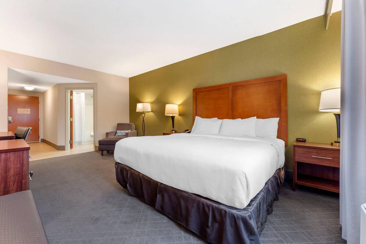 Una habitación de hotel con una cama grande, lámparas de noche, un escritorio y una silla.