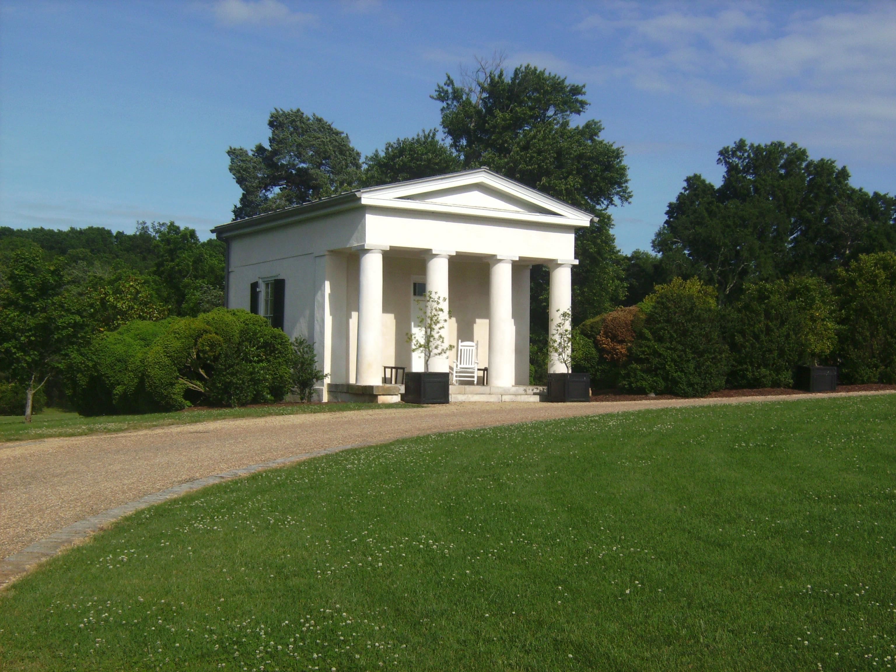 A white building with columns, a front door, and a small porch.