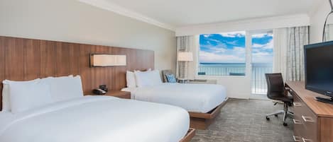Habitació d'hotel amb dos llits, un escriptori amb televisió i un balcó amb vistes.
