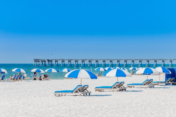 Na praia, areia branca, barracas de praia (sobretaxa), guarda-sóis 