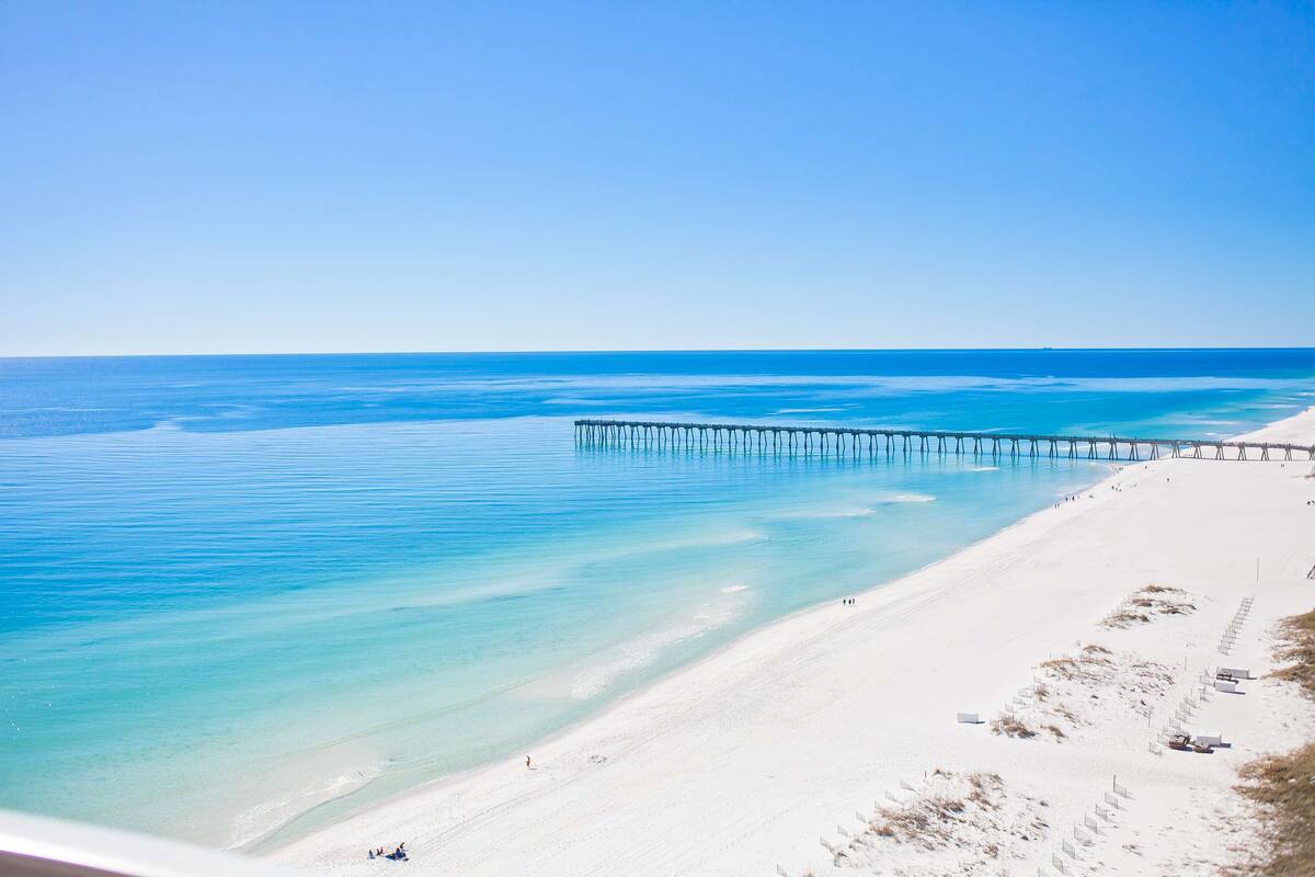 Une plage avec une jetée qui s’avance dans l’eau.