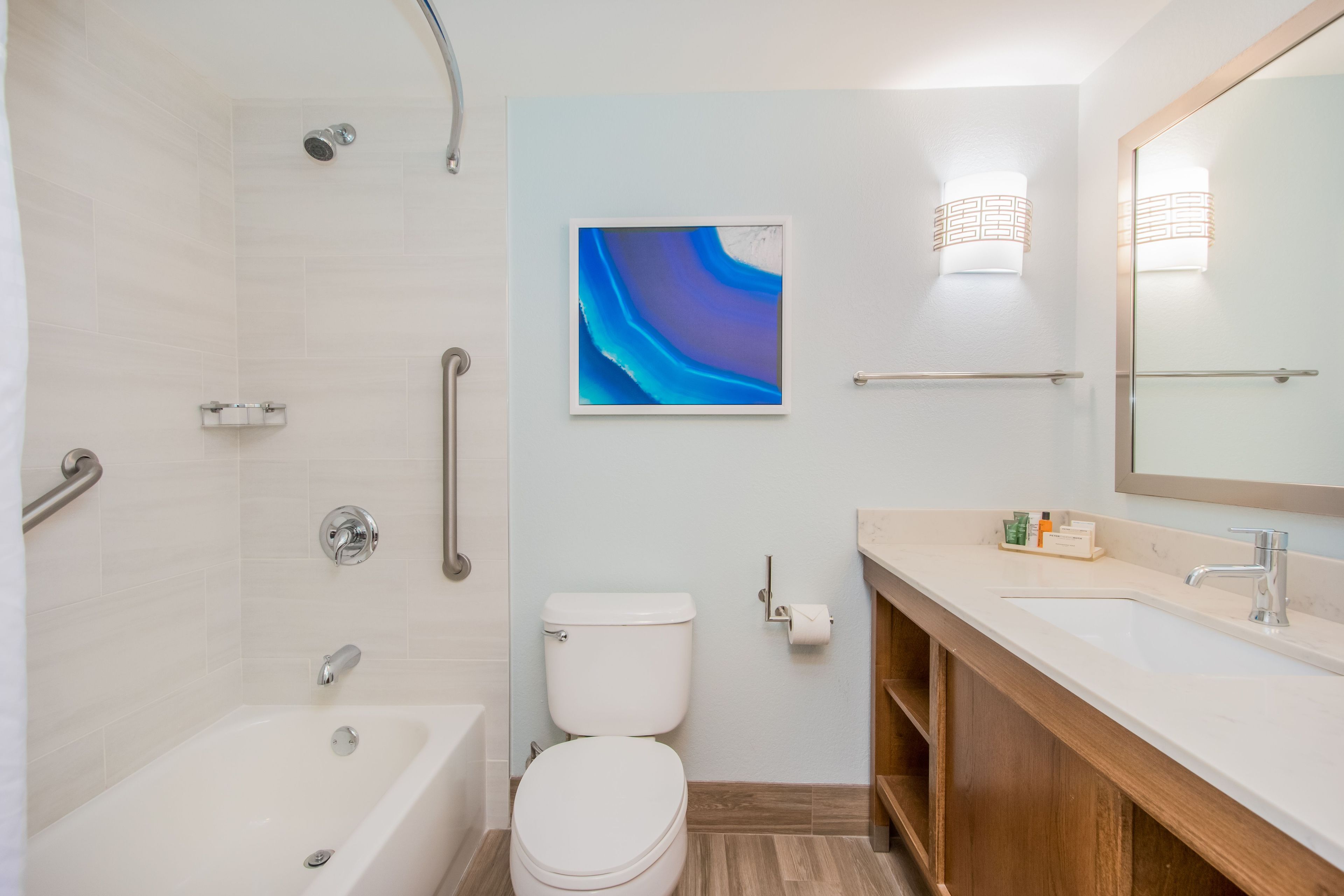A modern bathroom with a bathtub, toilet, and vanity with a mirror.