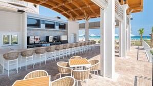 Un espace bar extérieur doté d’un long comptoir, de tabourets et offrant une vue sur la plage.
