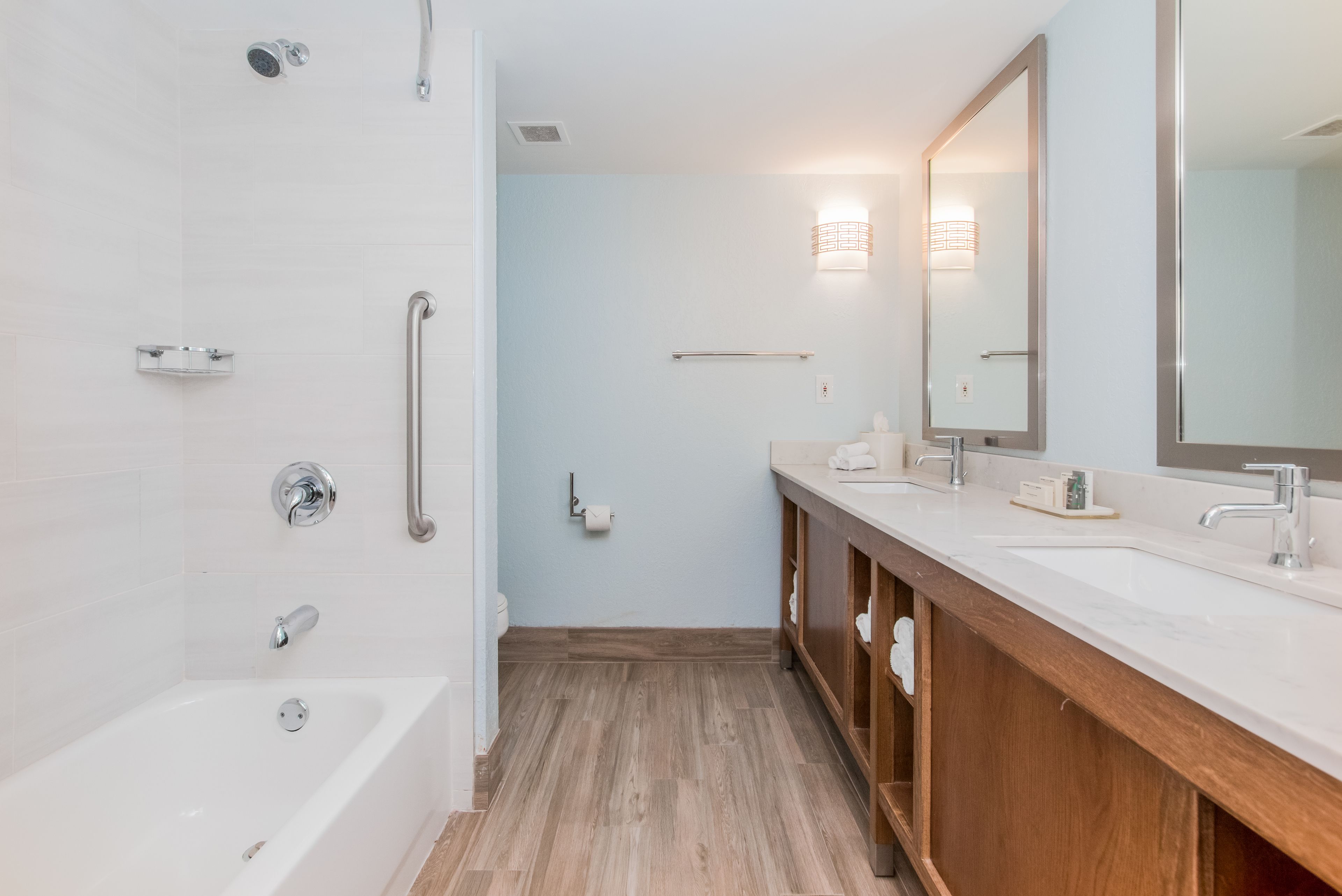 Un baño moderno con bañera, ducha, tocador con espejo e inodoro.