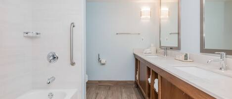 Et moderne badeværelse med badekar, brusebad, vaskebord med spejl og toilet.