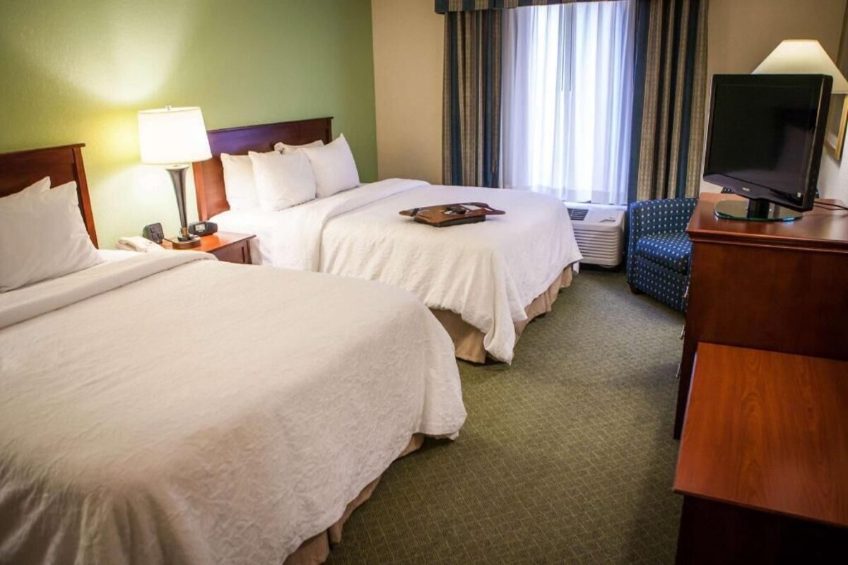 Une chambre d’hôtel avec deux lits, une télévision, un bureau et une chaise.