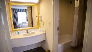 A hotel bathroom with a sink, mirror, and bathtub.