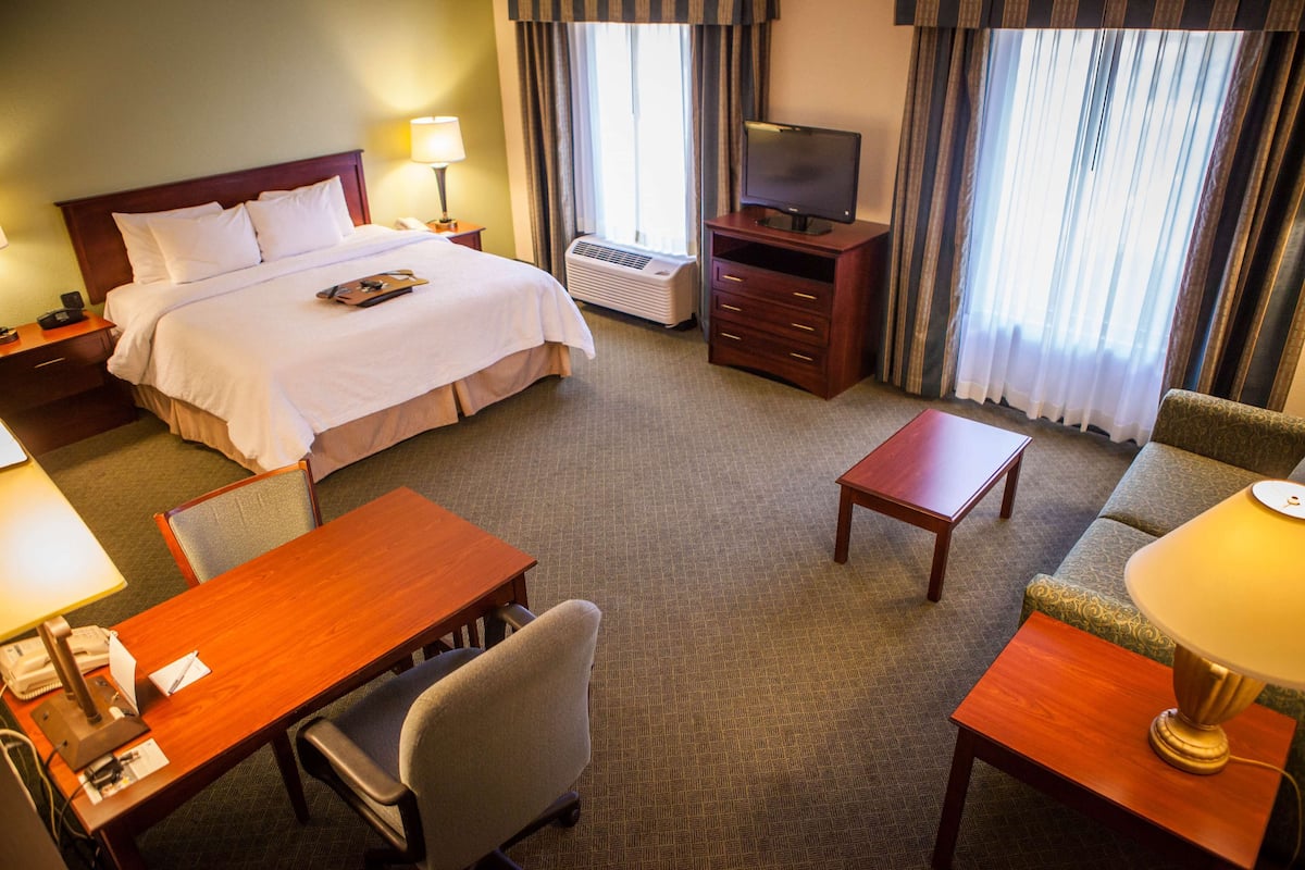 A hotel room with a bed, a TV, a desk, and a chair.