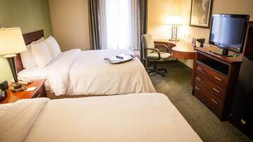 A hotel room with two beds, a desk with a computer, a chair, and a television.