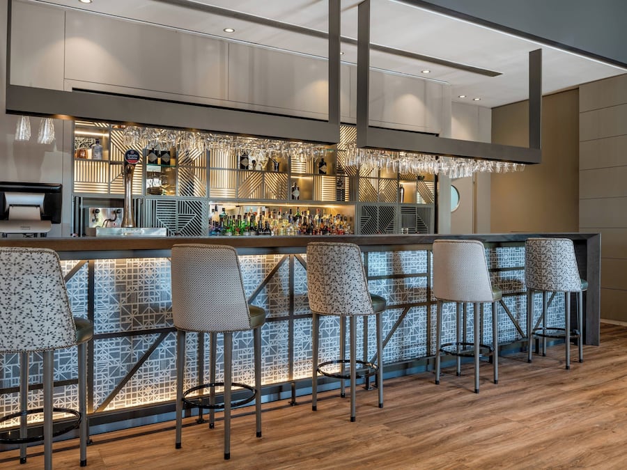 Een bar met een behang, barkrukken en een divers aanbod aan flessen.