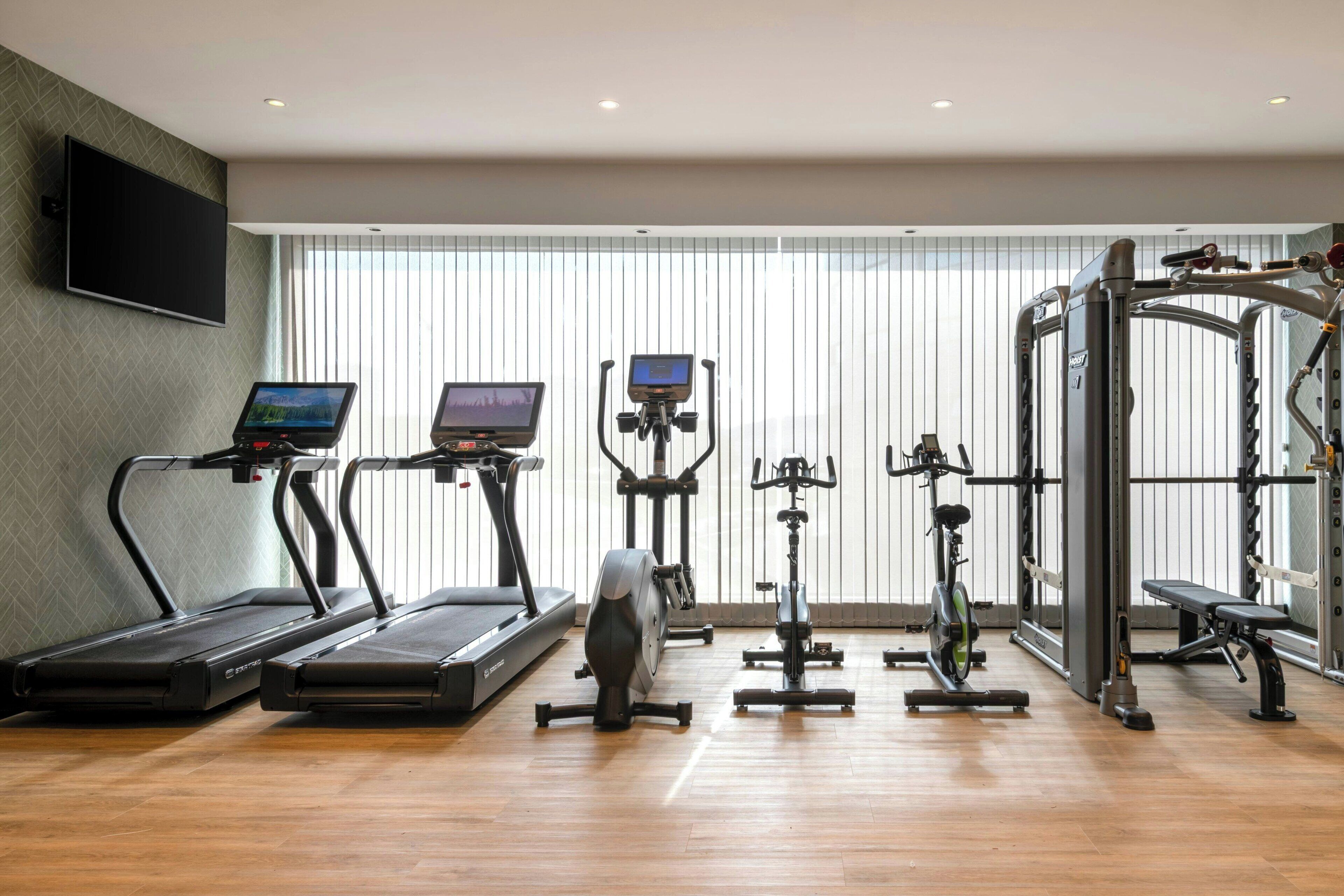 Un gimnasio con cintas de correr, bicicletas estáticas y una máquina de pesas.