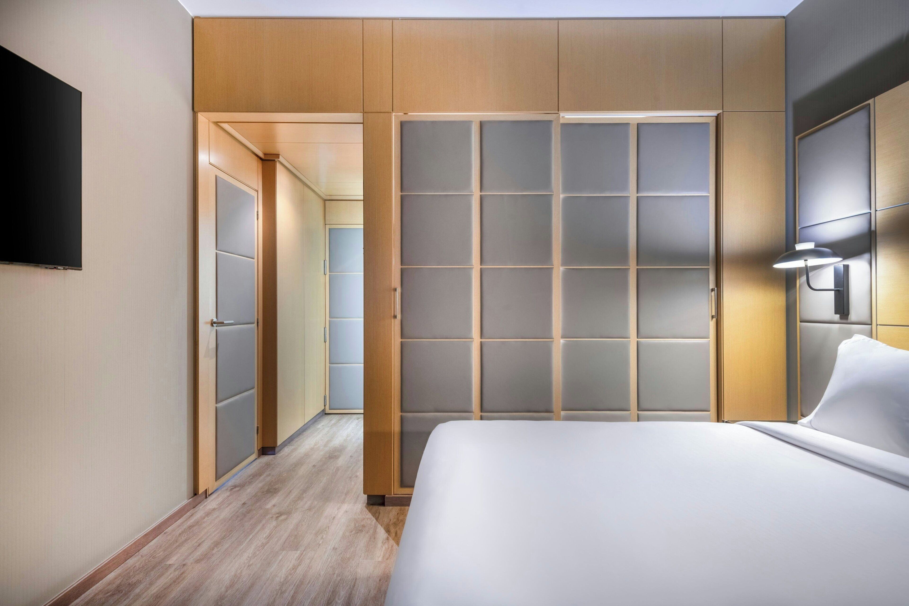 Een hotelkamer met een bed, een kledingkast en een televisie.