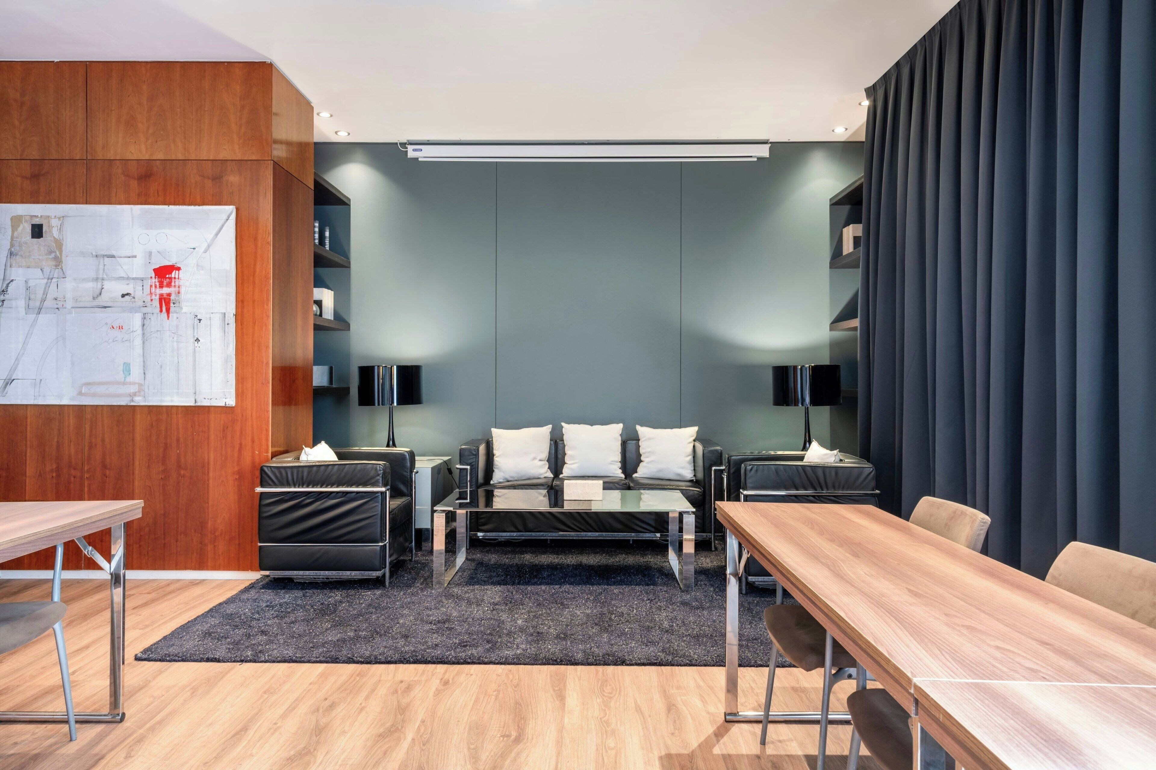 Une chambre d’hôtel moderne avec un bureau en bois, un canapé, une table basse et un téléviseur.