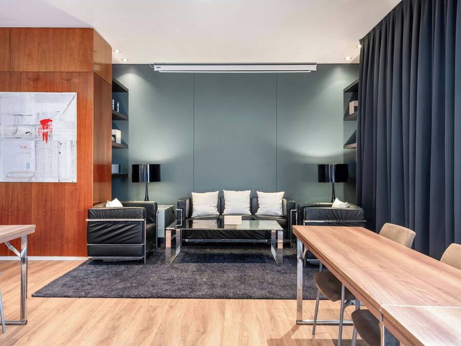Une chambre d’hôtel moderne avec un bureau en bois, un canapé, une table basse et un téléviseur.