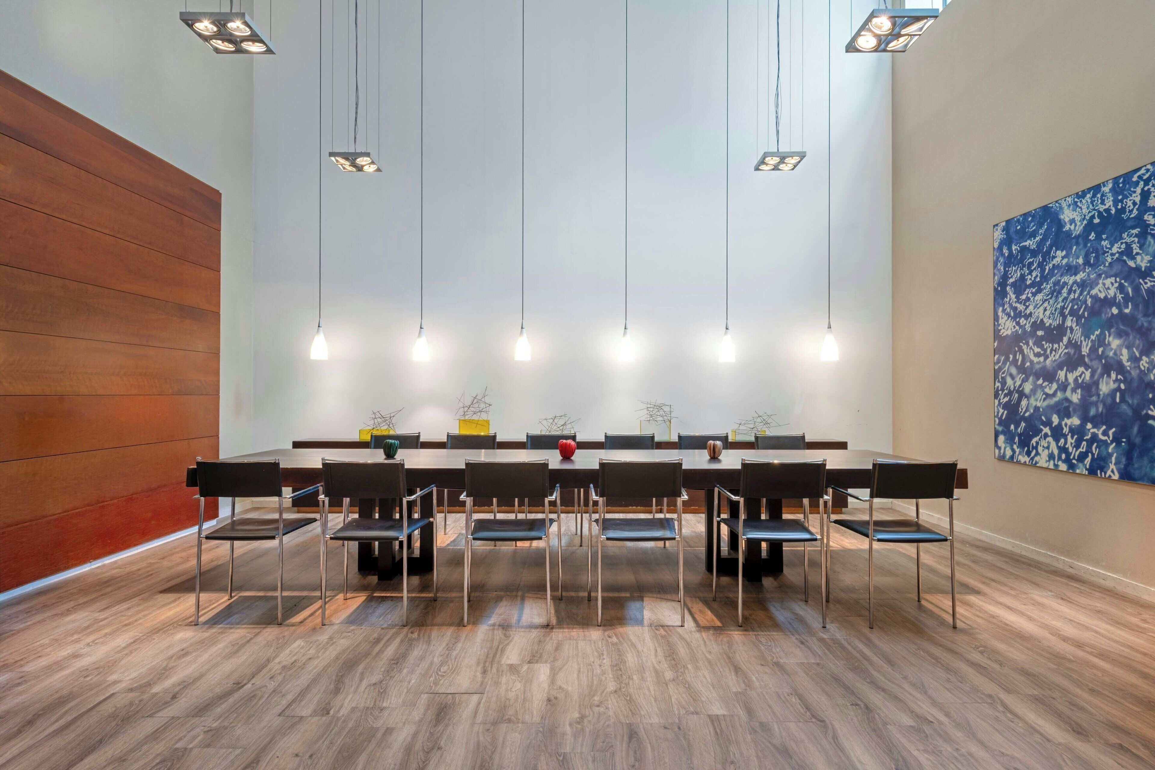 Un salón de conferencias con una mesa larga, sillas e iluminación colgante.