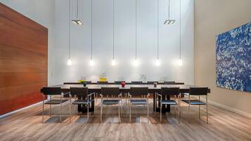 Un salón de conferencias con una mesa larga, sillas e iluminación colgante.
