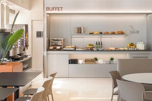 Uma área de buffet moderna, com diversos alimentos dispostos em prateleiras e balcões.