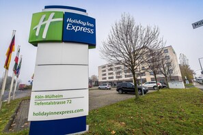 Ein Schild des Holiday Inn Express, im Hintergrund ist das Gebäude deutlich zu sehen.