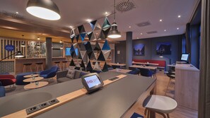 Un espace bar moderne comprenant un comptoir, des sièges et un écran numérique.