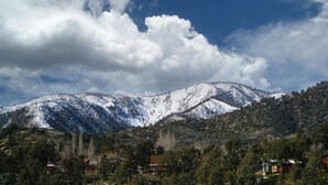 Un paisaje montañoso con picos nevados, cielo despejado y casas dispersas.