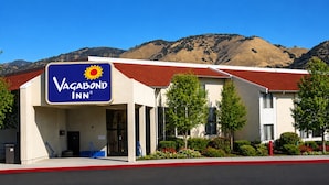 Edificio del VAGABOND INN con techo rojo, rodeado de vegetación y montañas al fondo.