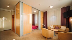 A hotel room with a sofa, armchairs, a small table, a TV, and a sliding door closet. - Rixwell Viru Square Hotel (Tallinn)
