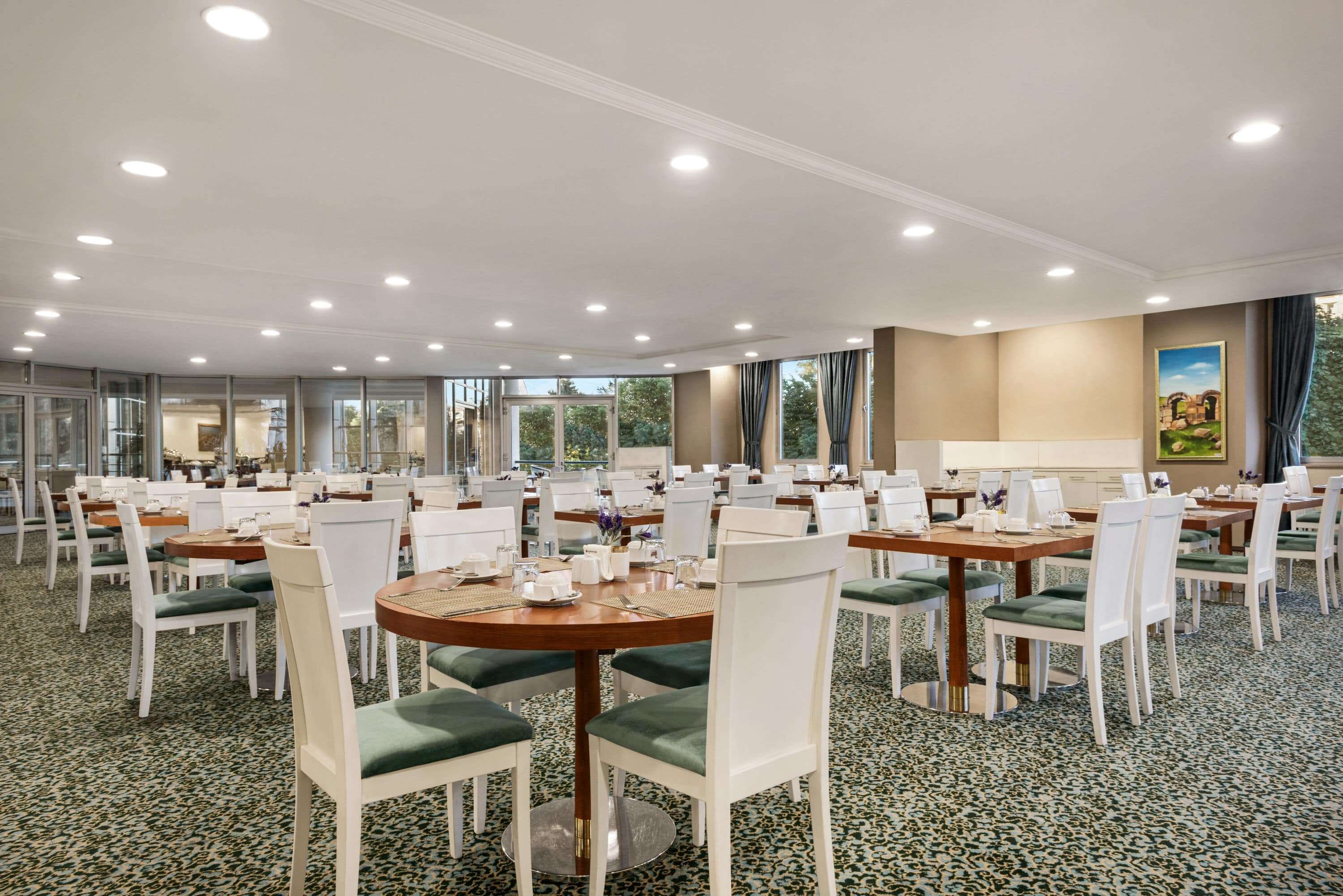 A large conference room with multiple round tables, white chairs, and a carpeted floor.
