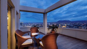 A balcony with wicker furniture and a view of a cityscape and mountain. - Wyndham Grand Kayseri (Kocasinan)