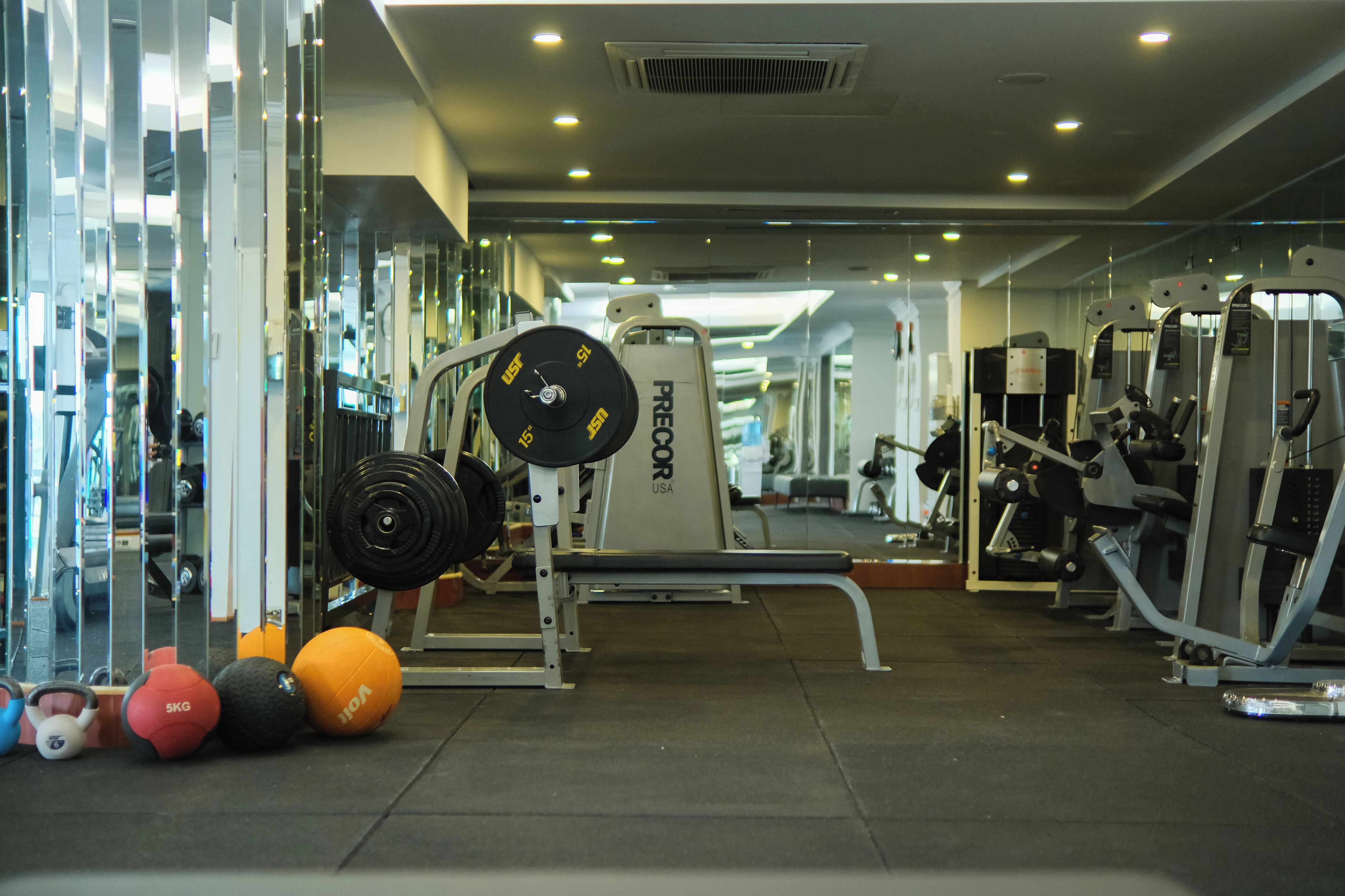 Un gimnasio con equipo de ejercicio variado, incluyendo un rack de sentadillas, banco de pesas y pesas sueltas.