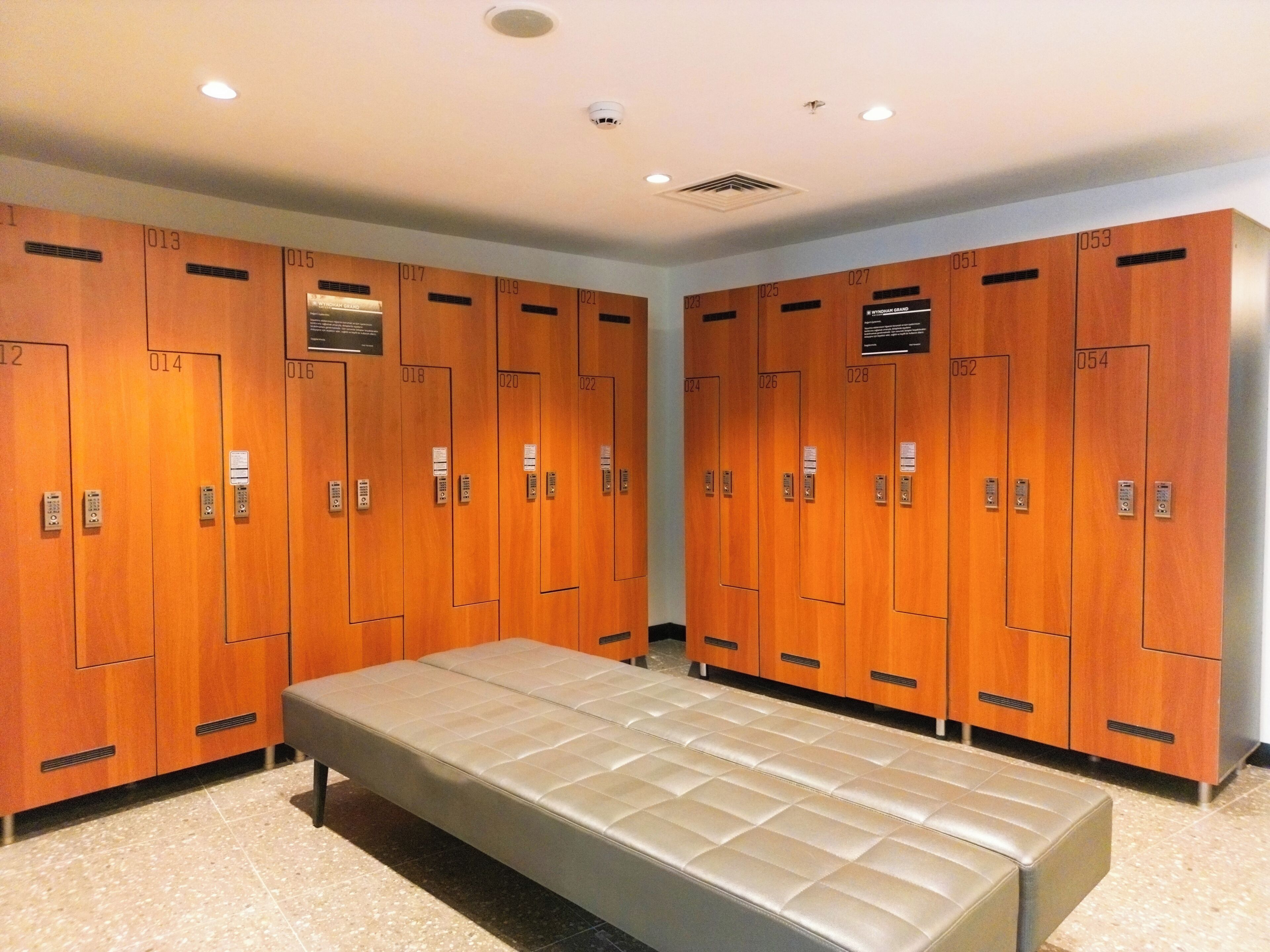 A row of wooden lockers with numbers, a bench, and a ceiling light.