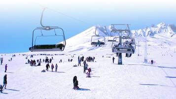 A ski lift with multiple chairs moving up and down a snowy slope.
