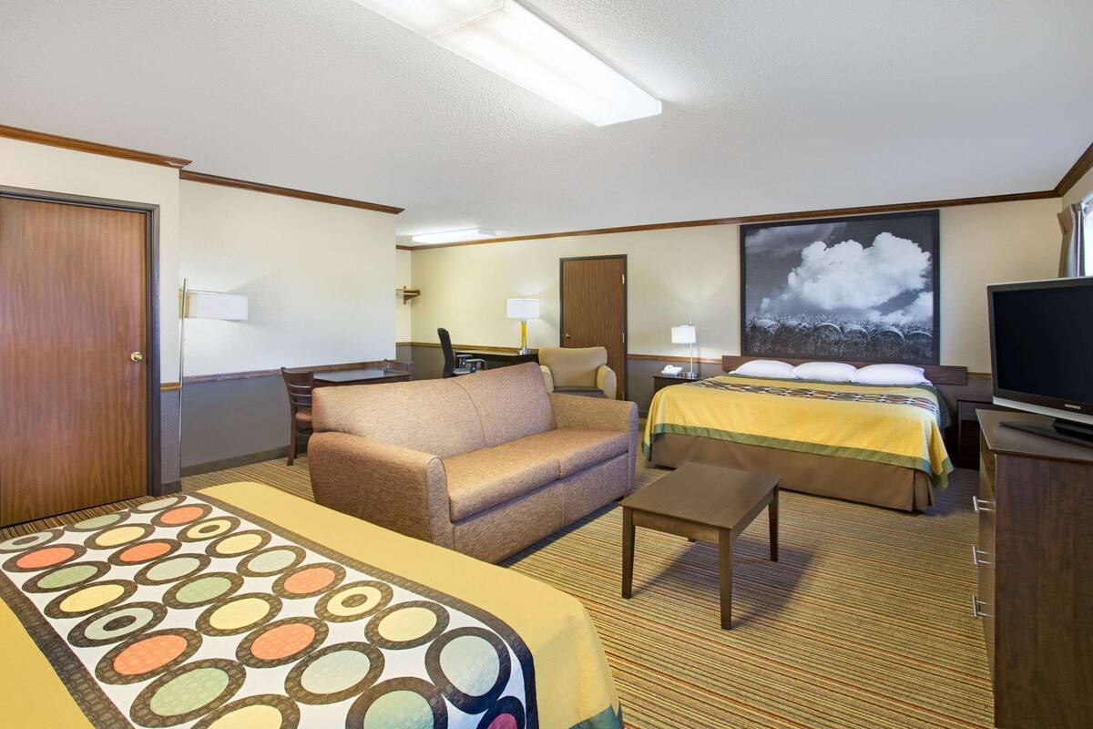 Ein Hotelzimmer mit Bett, Sofa, Schreibtisch, Fernseher und einem großen Fenster.