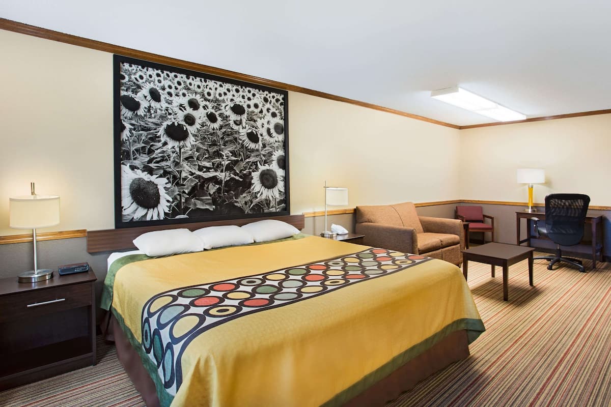 Ein Hotelzimmer mit einem großen Bett, einem Schreibtisch, einem Sessel und einem Sofa.