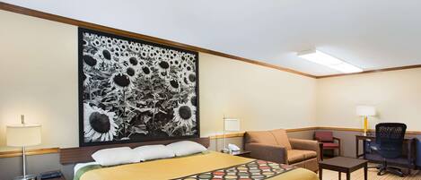 A hotel room with a large bed, a desk, a chair, and a sofa.