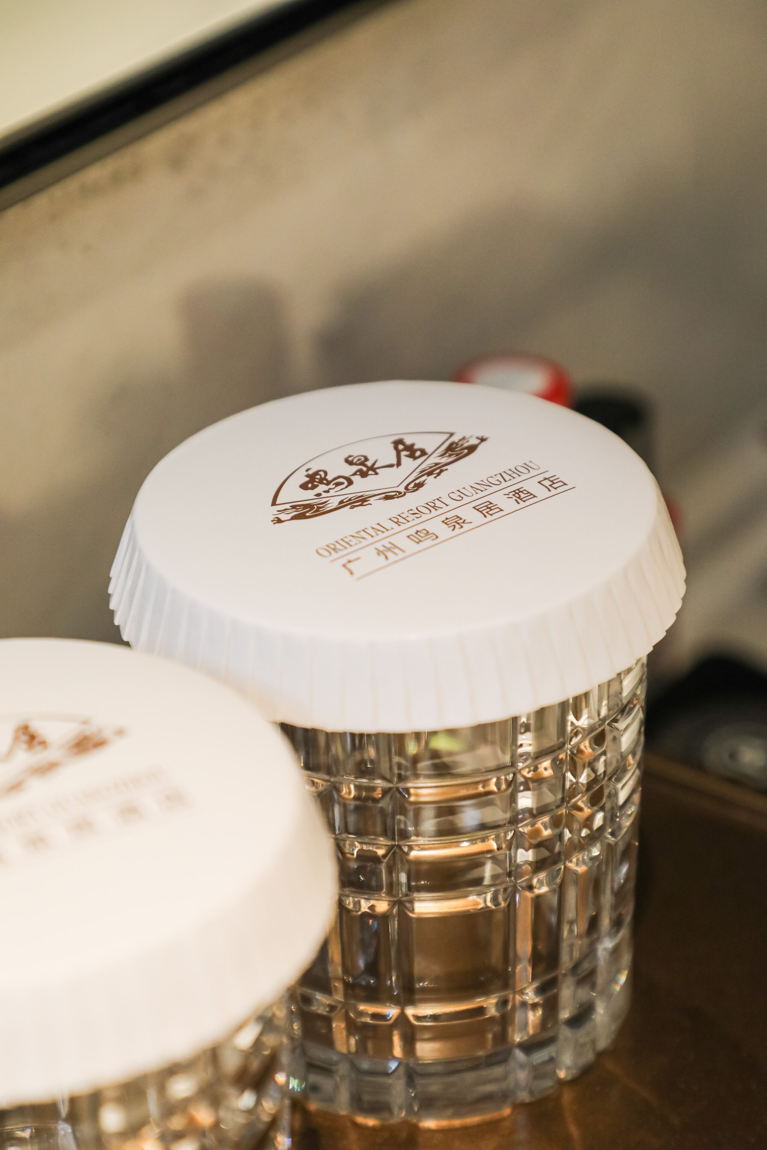 A close-up of two glass containers with white lids, one of which has a logo and text indicating a brand or establishment.