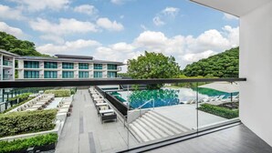 Un hotel moderno con piscina en la azotea, zona de estar al aire libre y vistas a exuberante vegetación.