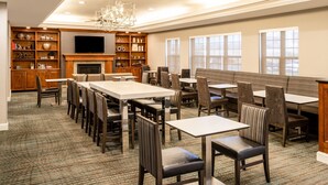 A dining area with multiple tables and chairs, a fireplace, and a television. - Residence Inn by Marriott Colorado Springs North/Air Force Academy (Colorado Springs)