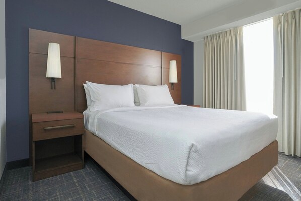 Une chambre d’hôtel avec un grand lit, deux tables de chevet et une petite table d’appoint.