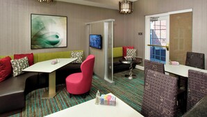 A hotel room with a sofa, a red chair, a table, and a TV. - Residence Inn by Marriott Colorado Springs North/Air Force Academy (Colorado Springs)