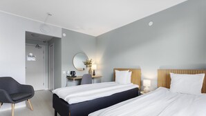 Une chambre d’hôtel avec deux lits, un bureau, une chaise et un miroir.